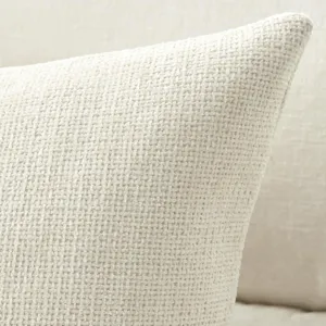 Close-up view of textured chenille cushion fabric in cream white for cozy sofa decor.