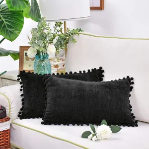 Elegant coussin en chenille noir avec des pompons pour canape de salon et decoration.