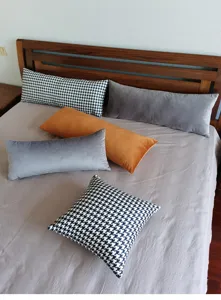 Vue détaillée d'un long coussin de lit et d'un oreiller en pied-de-poule et velours uni.