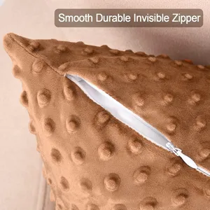 Primer plano detallado de funda de cojín marrón de puntos con cremallera invisible suave.