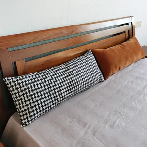 Long oreiller de lit, motif pied-de-poule noir et blanc et coussin lombaire marron.