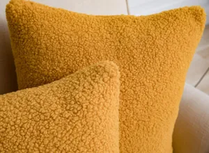 Textured mustard yellow sherpa throw pillow cover detail, soft fleece fabric cozy close-up.