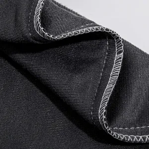 Vue rapprochée d'un tissu en velours foncé avec des coutures overlock blanches soignées.