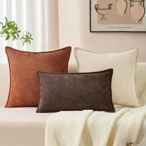Detailansicht von nordischen Chenille Kissenbezügen und Lendenkissen auf Sofa mit Decke.