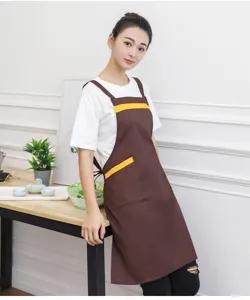 Detail view of a brown cotton apron with yellow trim, worn in kitchen or salon setting.