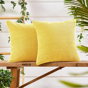 Gros plan détail des housses de coussin carrées texturées jaunes sur banc en bois.