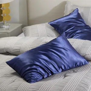 Vue détaillée de l'oreiller de corps en satin avec tissu bleu lisse sur un lit.