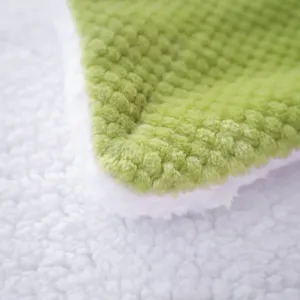 Detailed view of dual-sided fleece throw blanket, soft green grid and plush white Sherpa.