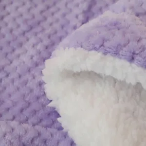Close-up of double-sided fleece blanket with soft purple textured face and cozy white sherpa.