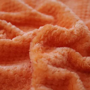 Close up view of soft orange flannel blanket fabric showing rich plush texture and cozy folds.