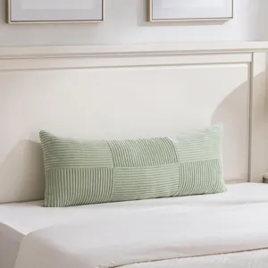 Detailaufnahme des langen salbeigruenen Kordkissens mit feiner Textur im Schlafzimmer.