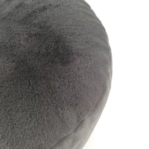 Close-up detail of soft dark gray plush fabric, showing fluffy texture of round minimalist pouf.