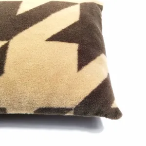 Gros plan détail de coussin en peluche motif pied-de-poule, texture douce et design chaleureux.