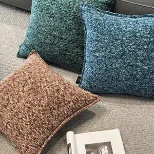Gedetailleerd overzicht van getextureerde chenille kussens in blauw, groen en bruin op tapijt.