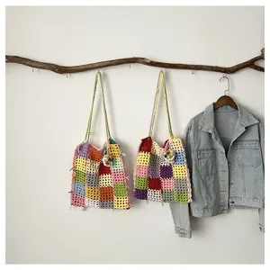 Vue détaillée de sacs cabas au crochet colorés faits à la main sur une branche.