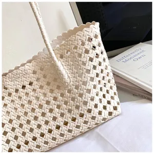 Gedetailleerde close-up van de elegante beige geweven tote tas, met een prachtige textuur.