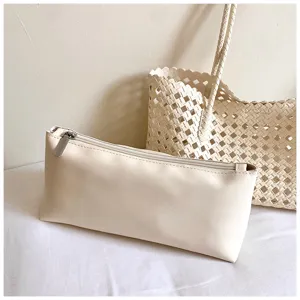 Minimalistische beige etui en holle geweven tote tas voor dagelijks gebruik en vakantie.