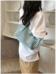Gedetailleerd overzicht van een lichtblauwe, holle gewoven schoudertas met fijn mesh vakmanschap.