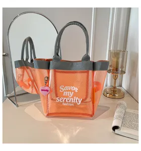Transparent orange mesh tote bag detail showing chic front text and pink heart charm pendant.