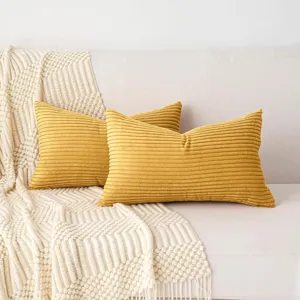 Close-up detail of soft yellow corduroy throw pillows showcasing textured stripes on a cozy sofa.