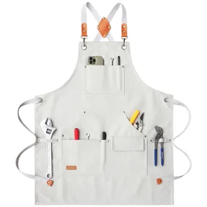 Heavy duty canvas work apron with cross back leather straps and multiple tool pockets detail.