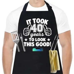 Vista detallada de un delantal de cocina negro para hombre con texto blanco divertido y bolsillos.