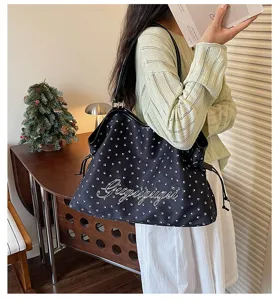 Sac cabas bandoulière noir en toile avec motif d'empreintes de pattes et lettrage élégant.