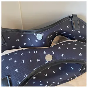Sac bandoulière en toile noire avec motif d'empreintes de pattes et bouton aimanté.