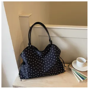 Sac cabas noir avec motif de pattes blanches, détail de sac à bandoulière de grande capacité.