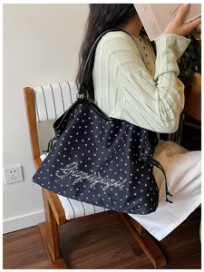 Vue détaillée du sac cabas noir avec motif de pattes blanches, grand sac bandoulière casual.