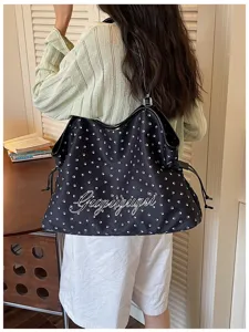 Vue de détail du sac cabas en toile noire avec motif d'empreintes et broderie.