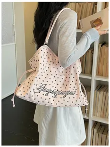 Vue détaillée du sac fourre-tout rose avec joli motif d'empreintes et texte élégant.
