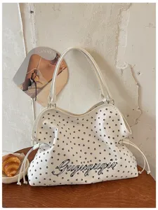 Vue détaillée du sac cabas blanc avec motif d'empreintes de pattes et cordons.