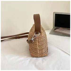 Bolso bandolera de paja tejida vista lateral, bolso de playa de verano con correa de cuero marrón.