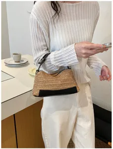 Primer plano de un bolso de hombro de paja elegante con ribetes de cuero negro para verano.