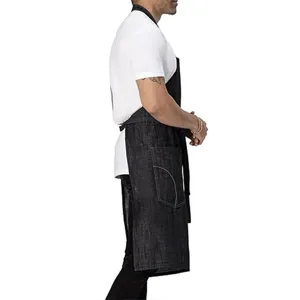 Detail view of black canvas apron with neck strap and front pocket, durable utility workwear.