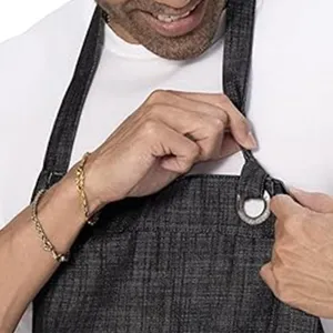 Cotton linen work apron detail view, adjustable neck strap and metal ring, durable fabric.