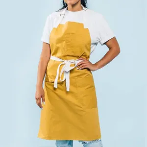 Delantal de trabajo de lona amarilla con lazos blancos y bolsillos prácticos para cocina y repostería.