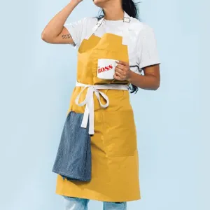 Delantal de cocina profesional de lona amarilla con tirantes cruzados blancos y bolsillos.