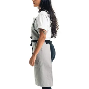 Delantal de trabajo gris de lona con tirantes negros para cocina, café y panadería.