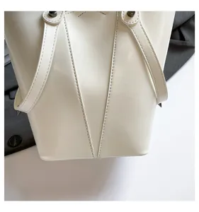 Primer plano de bolso saco blanco con costuras verticales y detalles de remaches de metal.