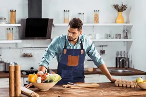 Kitchen apron with contrast PU leather pockets, durable denim style for BBQ and baking work.
