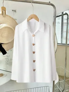 Dettagli della camicia bianca casual con bottoni metallici a cuore e spalle scese eleganti.