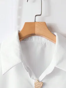 Camicia tinta unita con revers e grazioso bottone in metallo a cuore, stile retrò, dettaglio.