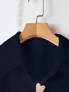 Primo piano del colletto della camicia blu scuro e dell'esclusivo bottone a cuore.