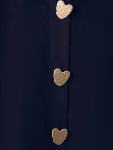 Dettaglio ravvicinato di camicia vintage tinta unita con bottoni a cuore dorati.