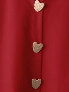 Primo piano dettagliato di una camicia rossa con bottoni dorati strutturati a cuore.