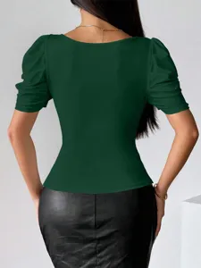 Vista di dettaglio di un top corto verde unito con scollo quadrato e maniche a sbuffo.