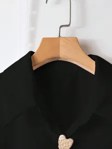 Vista dettagliata di camicia nera rétro unita con elegante bottone metallico a cuore.