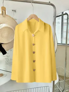 Dettaglio camicia maniche lunghe gialla, tinta unita vintage vestibilità ampia bottoni cuore.